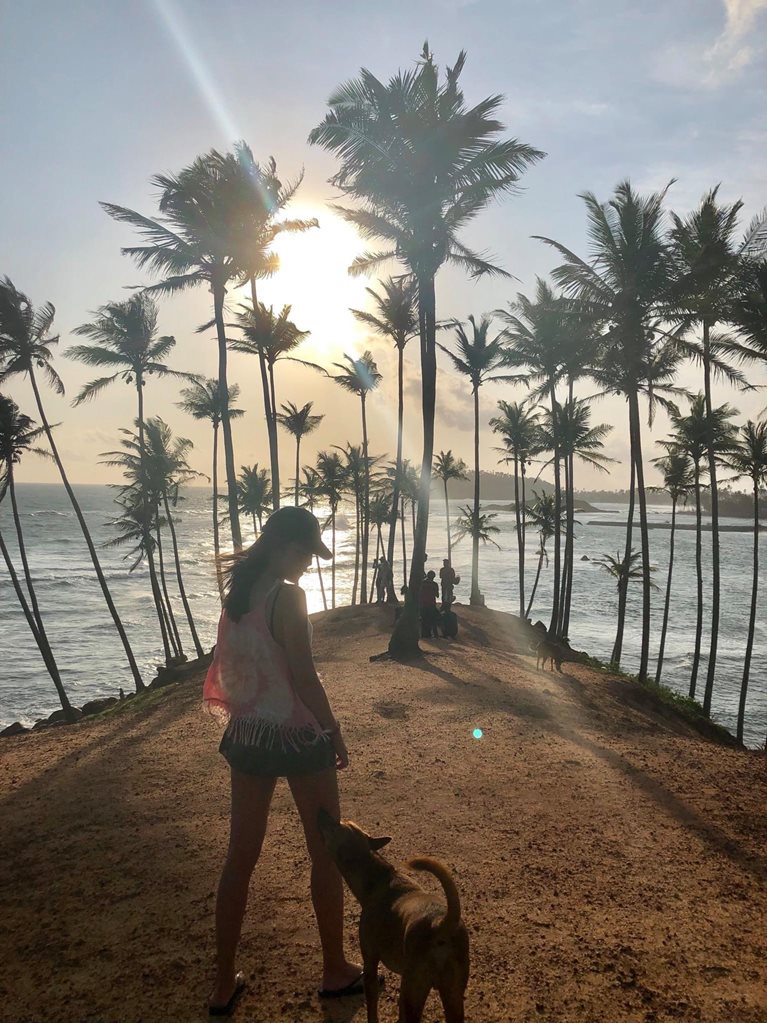 Mim with a dog on a beach at sunset