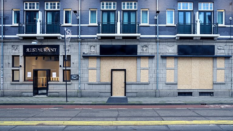 Empty and boarded-up storefronts with apartments above them. 